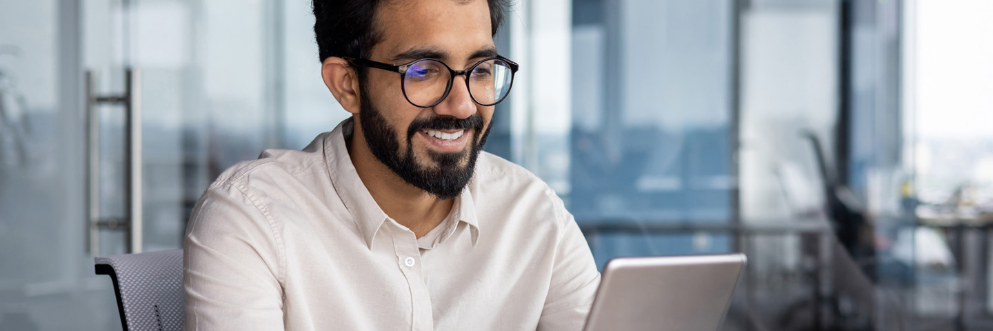 Image of man wearing glasses smiling at a tablet