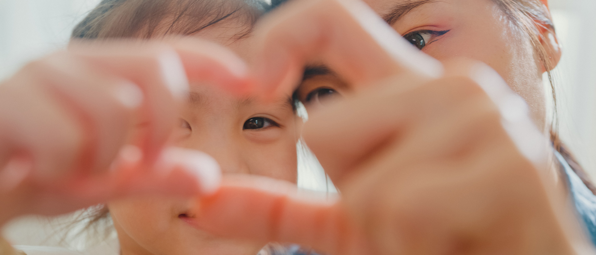 Mother and child making a heart with their hands