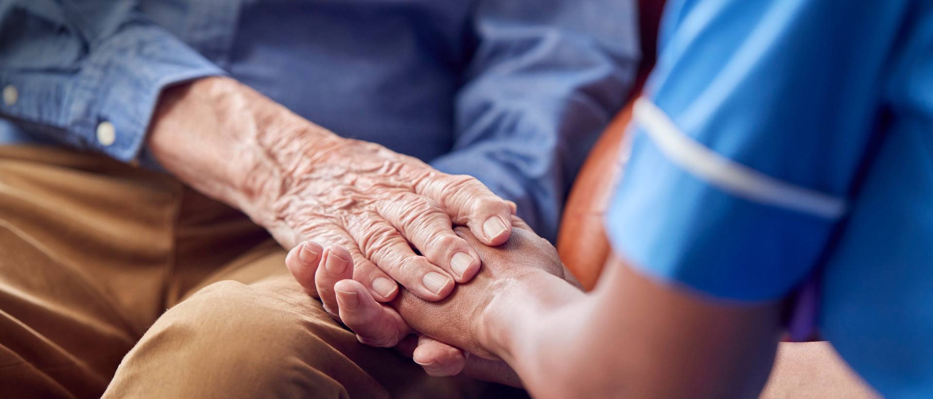 Older man holding hands with a nurse