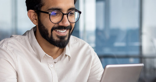 Close up image of man in glasses smiling at tablet