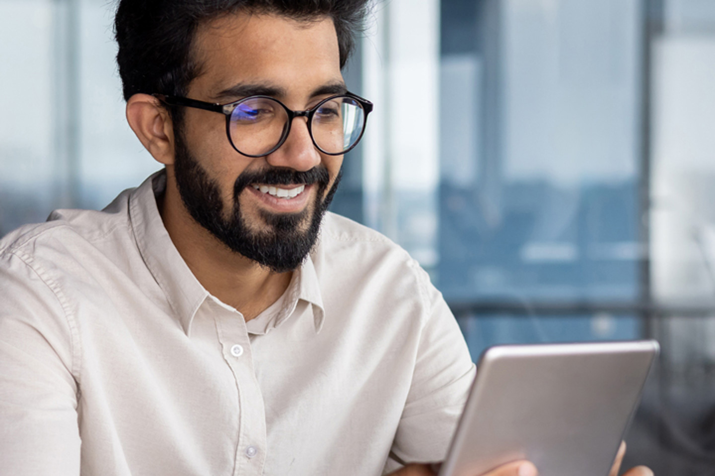 Close up image of man in glasses smiling at tablet
